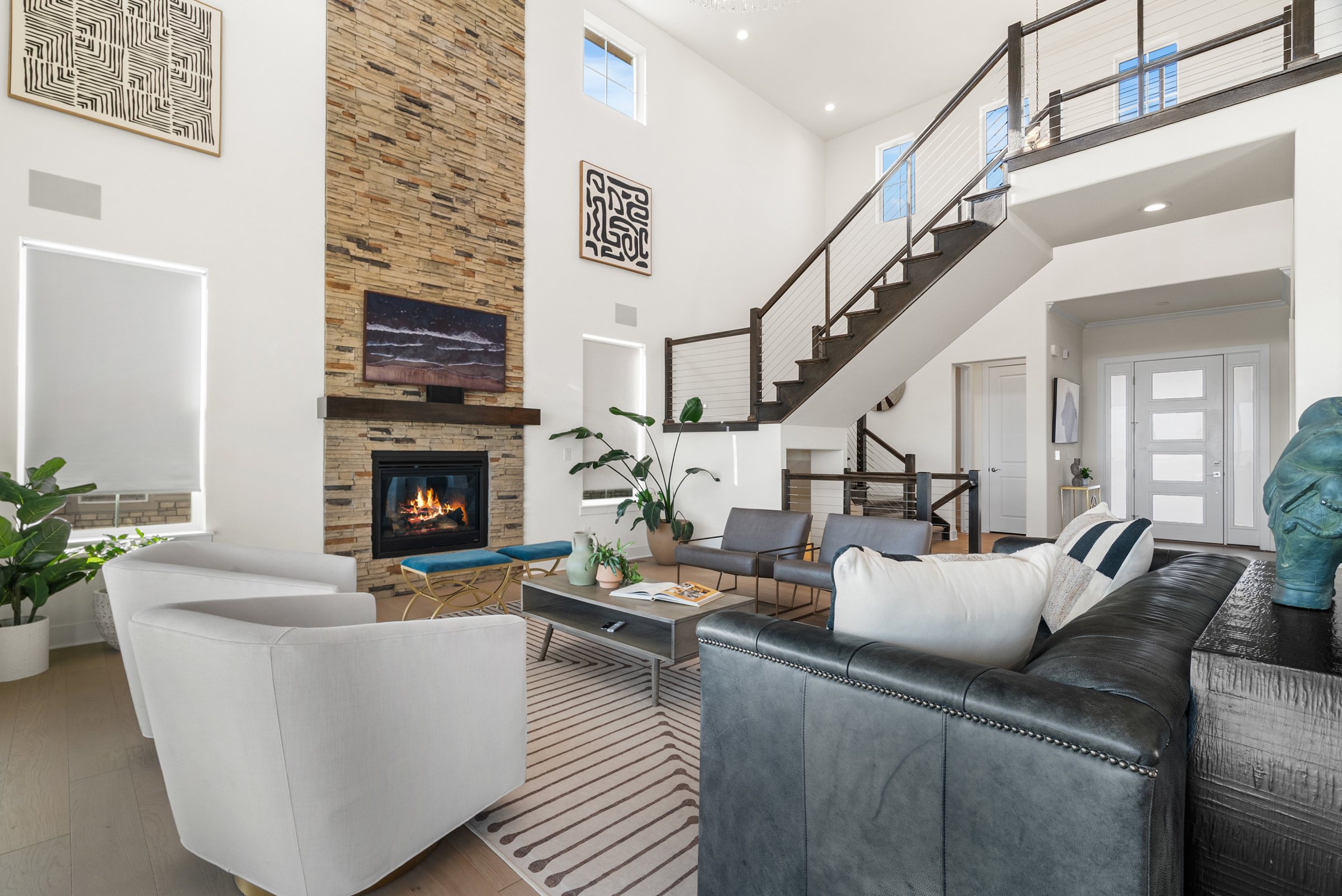 Two-story great room with fireplace, staircase, and view-facing seating.