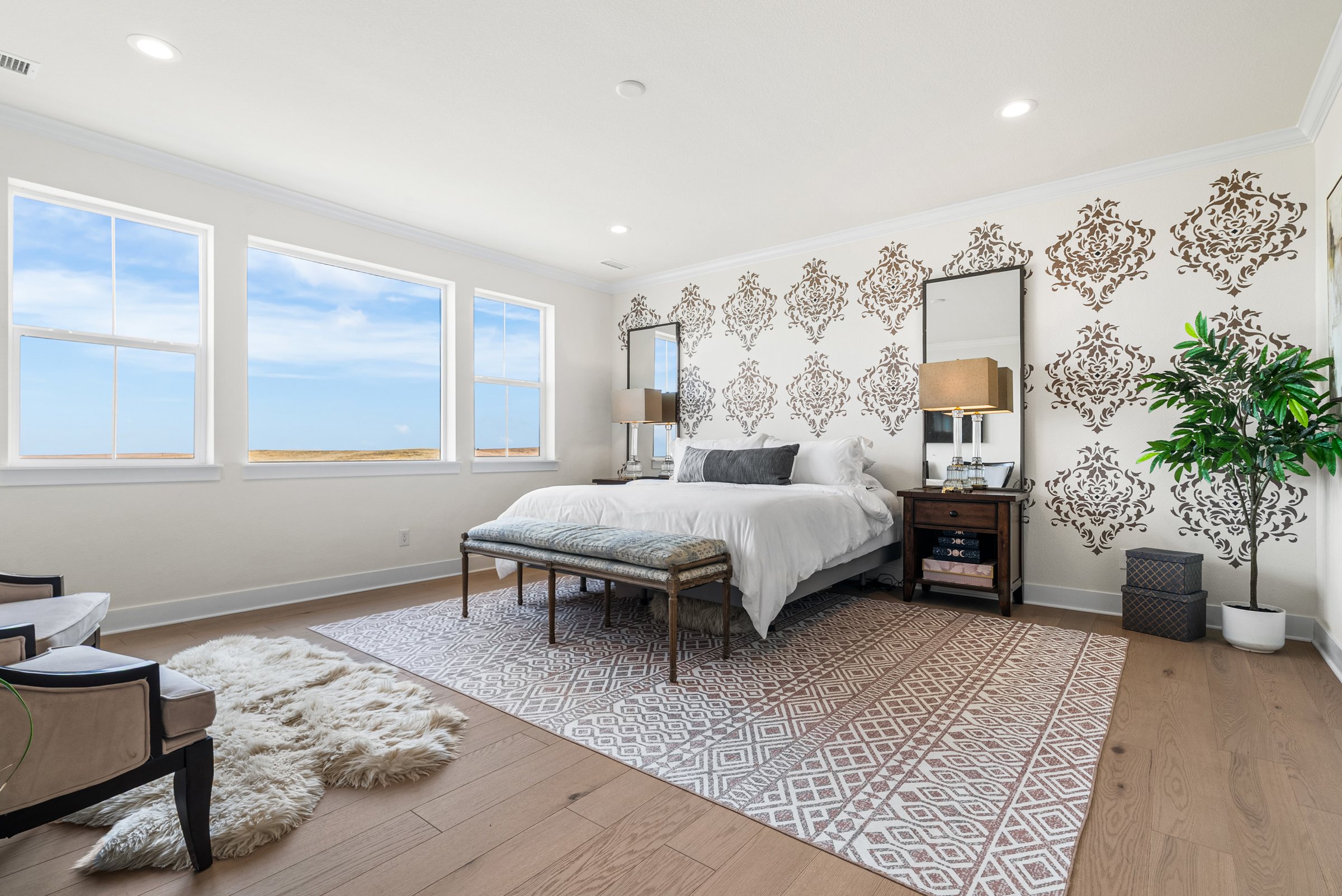 Upper primary suite with patterned accent wall and multiple windows.