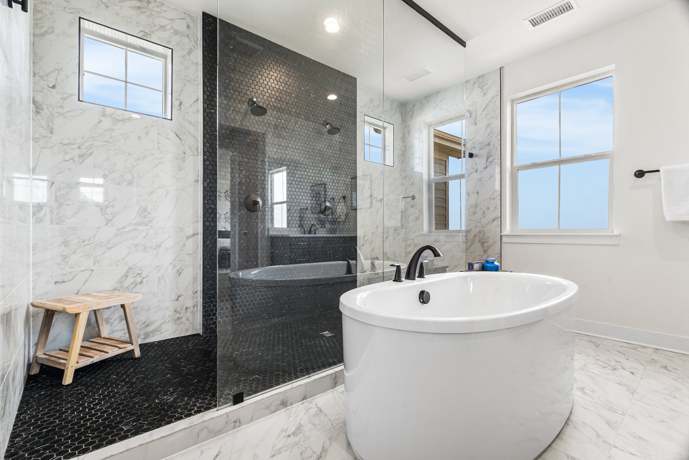 Primary bath showing freestanding tub and dark-tile shower.