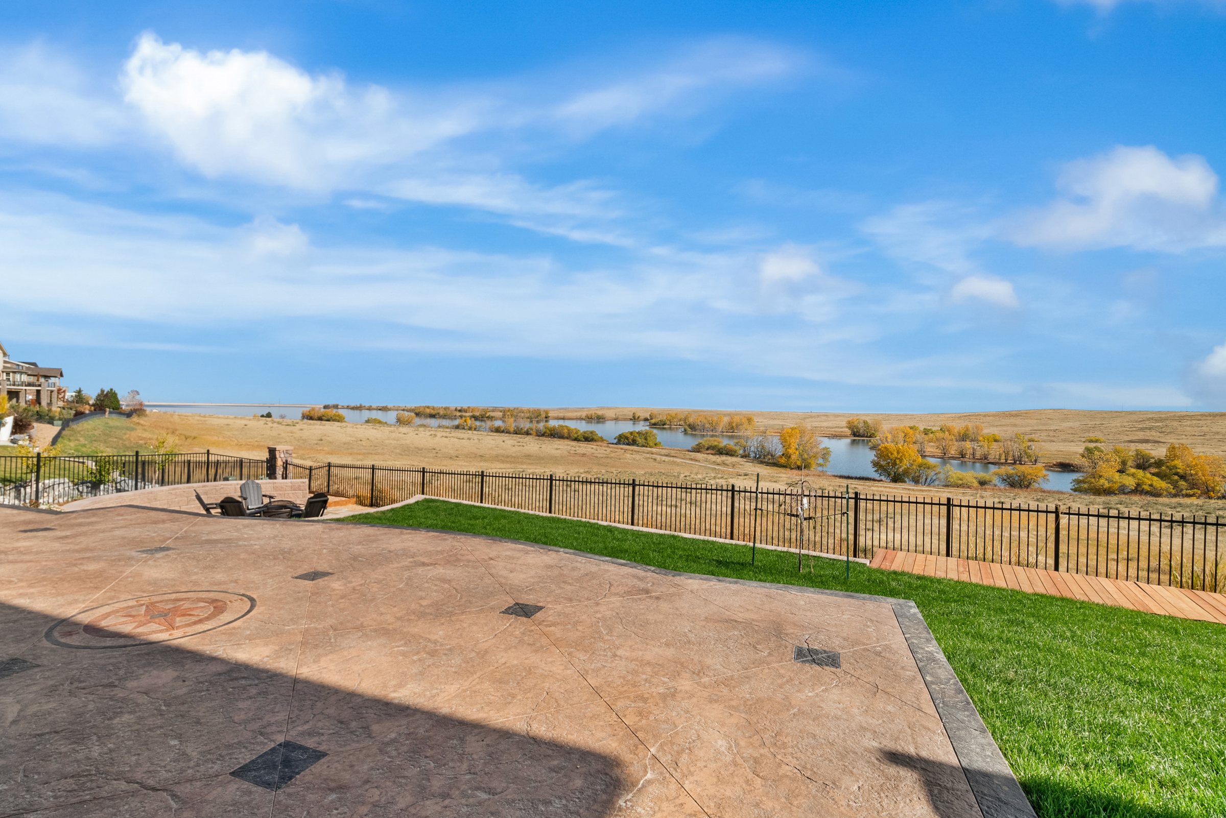 Patio and lawn overlooking open prairie and distant reservoir.