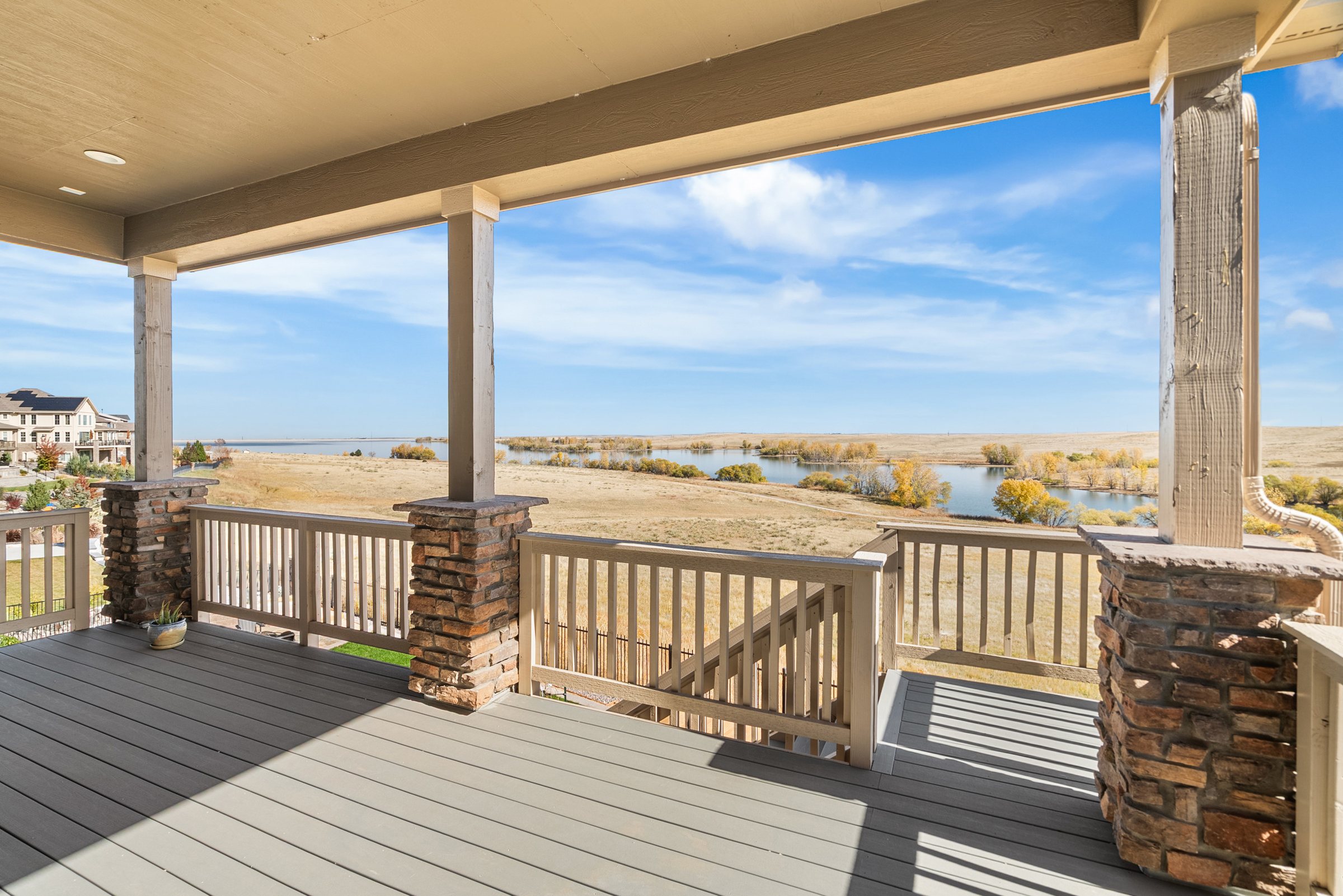 Covered deck overlooking open space and distant reservoir.