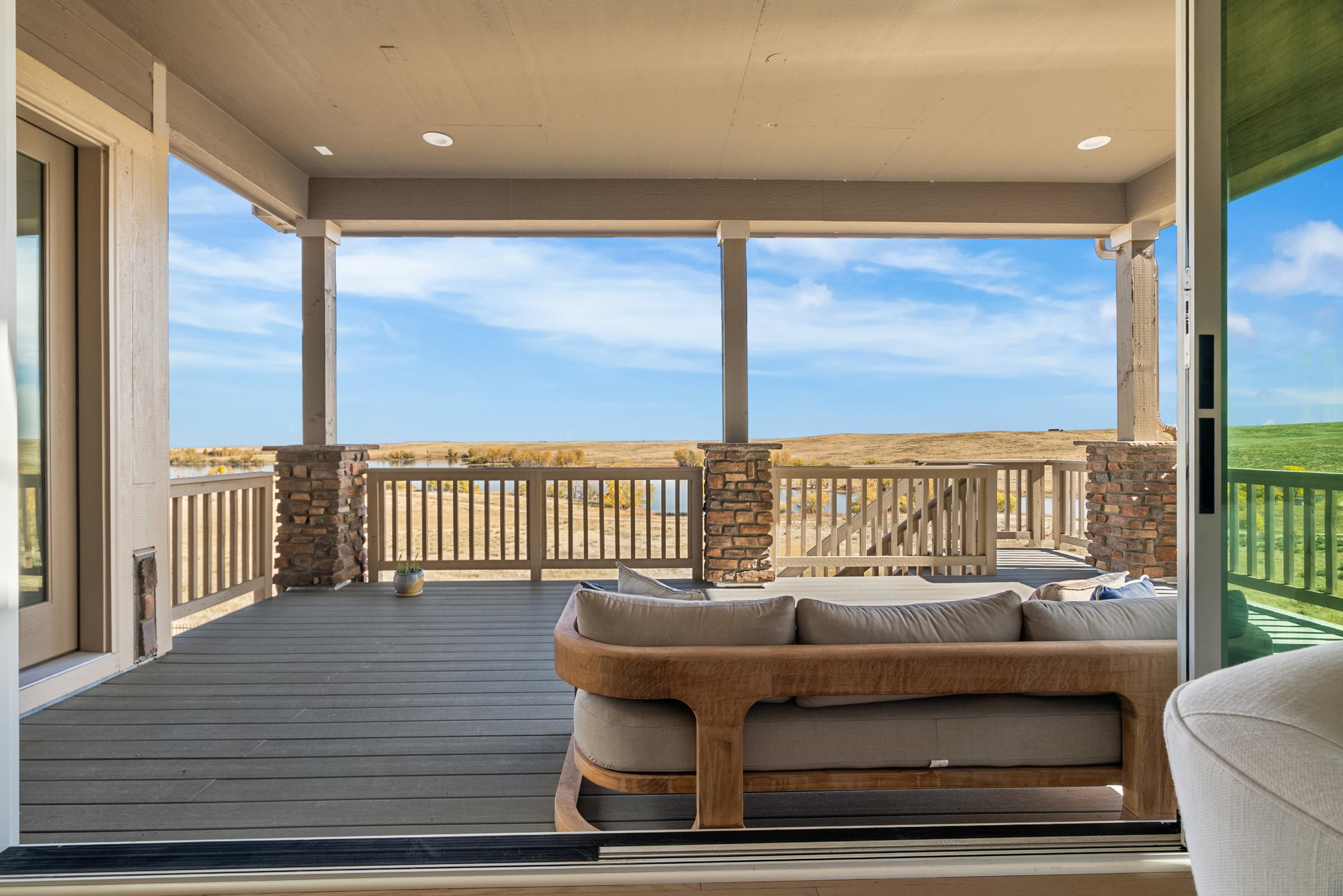 Covered deck seating framed by open prairie and distant reservoir.